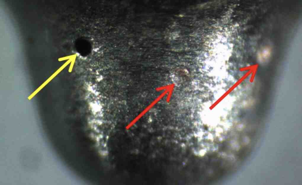 Magnified nozzle with arrows pointing at clogged spray holes