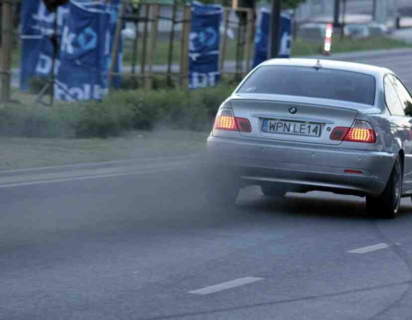Car on the road with visible smoke from the exhaust
