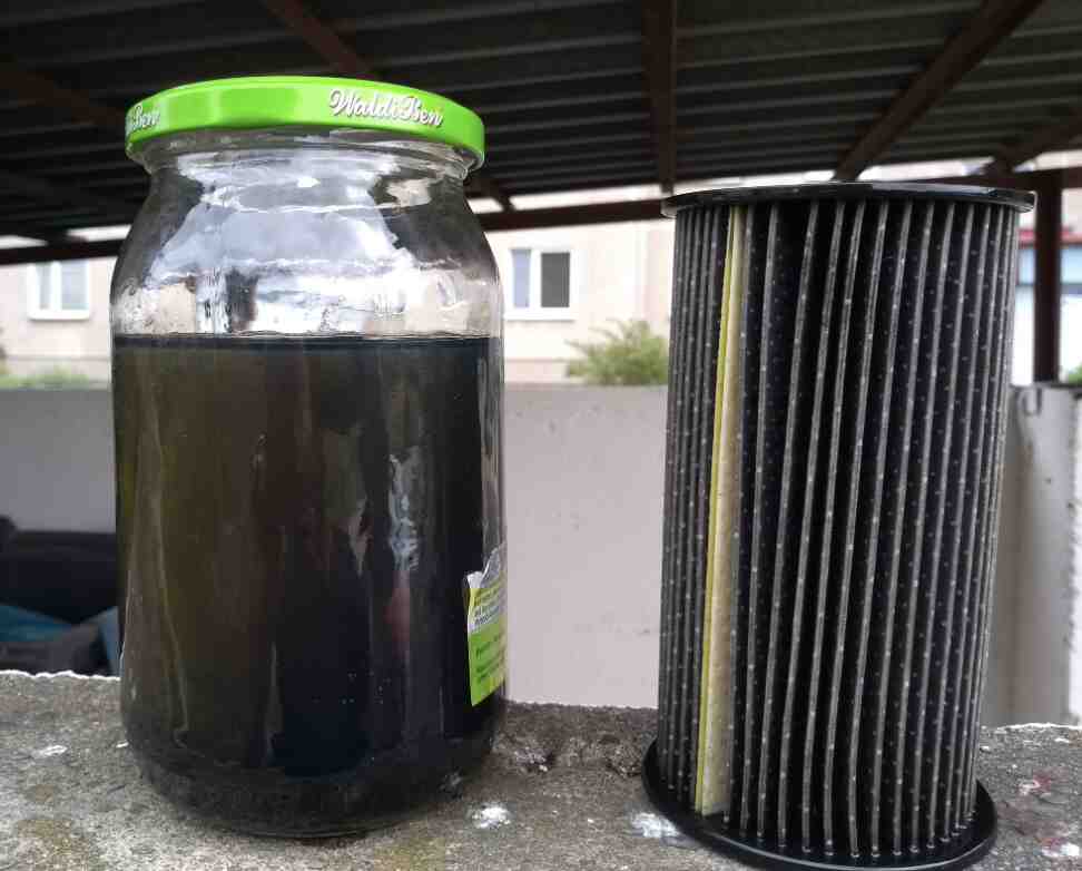 Jar of dark fuel beside a removed filter element
