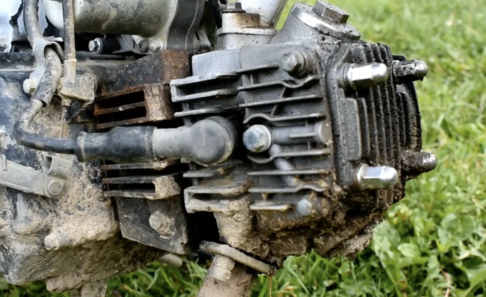 Zabrudzony, chłodzony powietrzem cylinder silnika motocykla pokryty osadami oleju i brudem