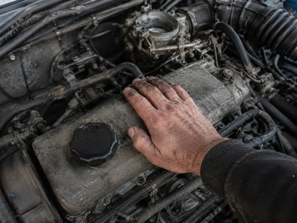 Dłoń mechanika oparta na pokrywie zaworów pracującego silnika