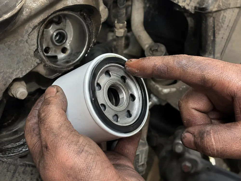 Mechanic finger oiling the sealing ring of a new oil filter