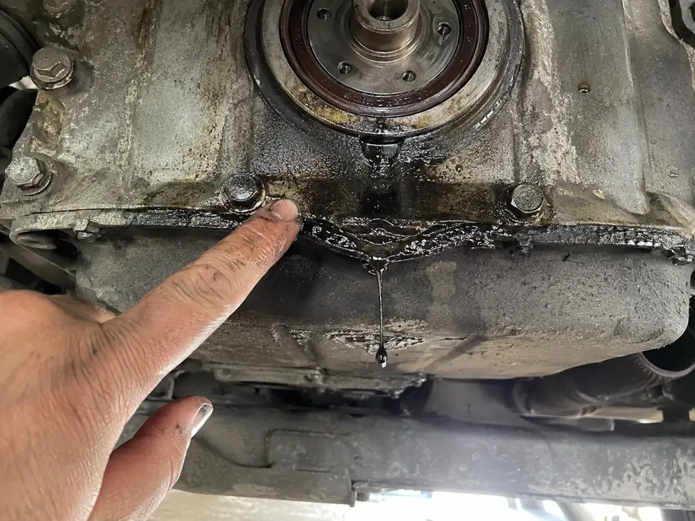 Fresh oil leak from the crankshaft seal, with a drip forming below