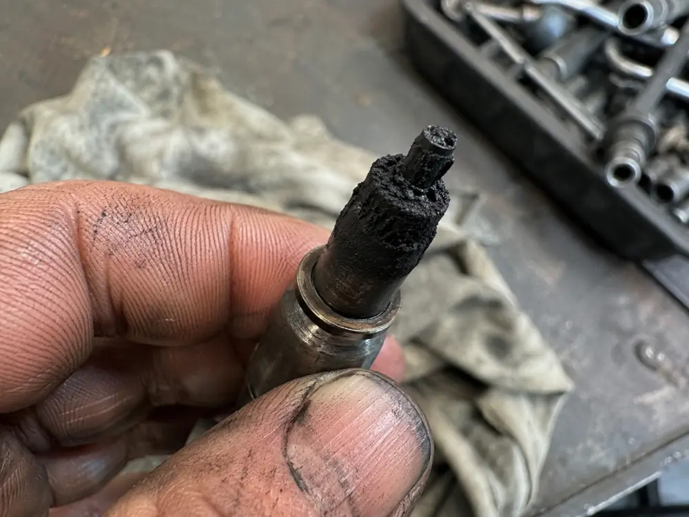 Coked tip of a diesel injector held in a mechanic hand